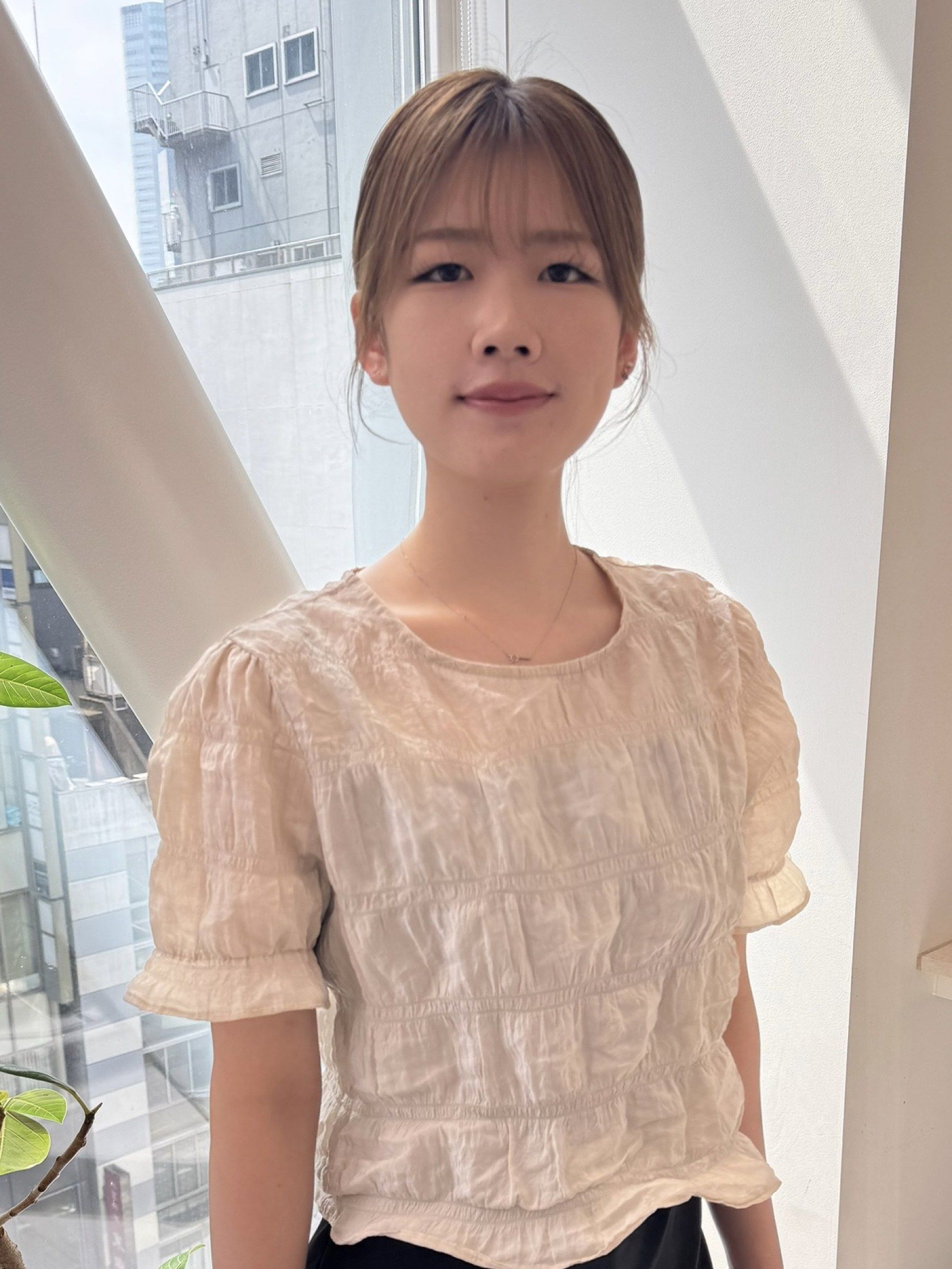 スタイリストの廣瀬 そら。前髪のある明るい茶色のまとめ髪で、生成りのブラウスを着ている