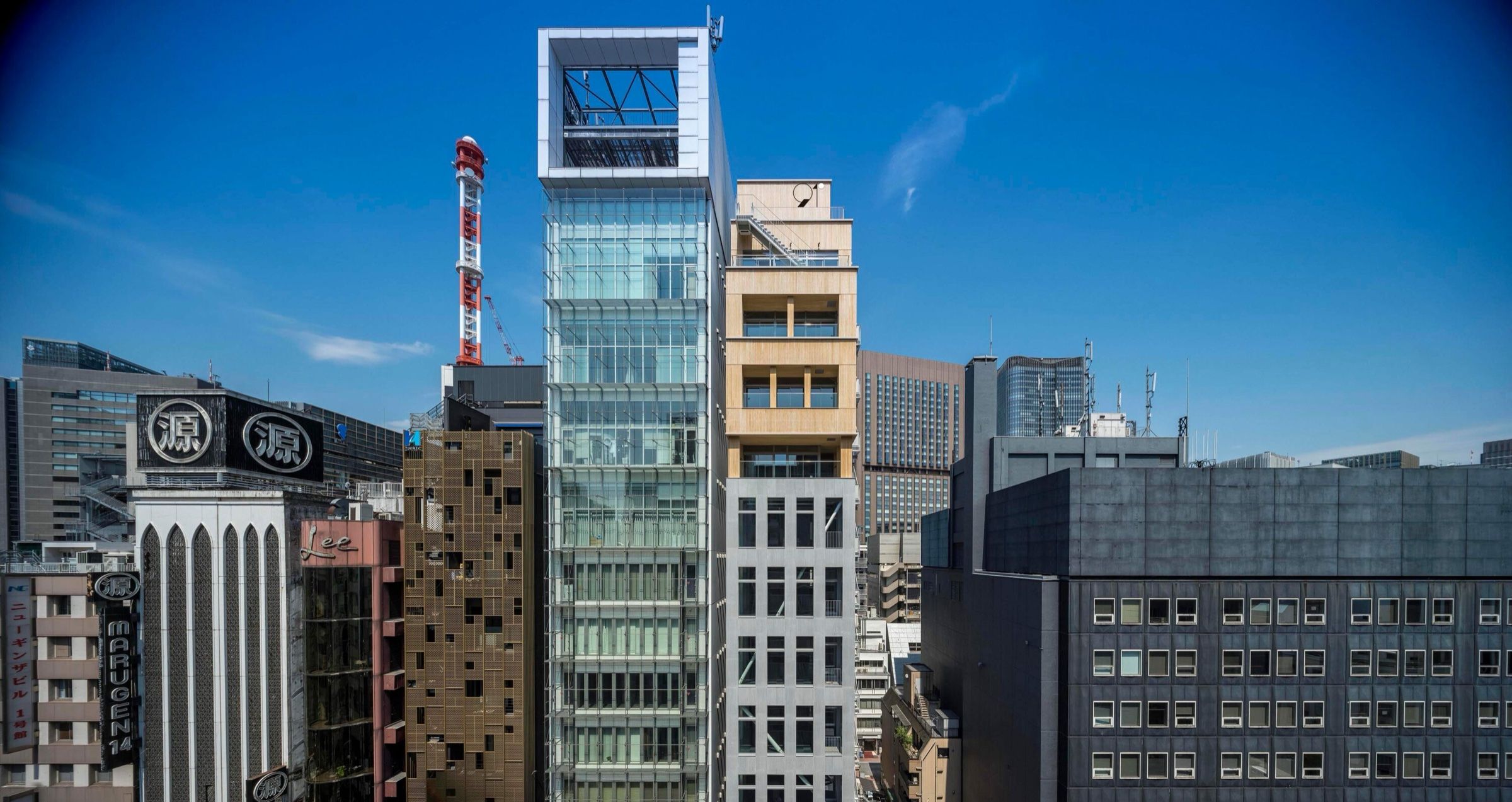 銀座の街並み。ガラス張りの高層ビルの右隣に、上層が木目調・下層がグレーの銀座高木ビルが建っている